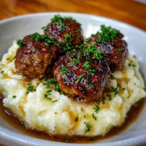 Salisbury steak meatballs served with garlic herb mashed potatoes in a beautiful dish.