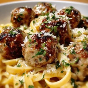 Delicious garlic butter meatballs atop creamy Parmesan linguine in a plate.